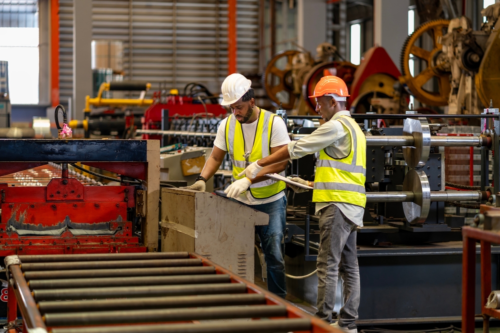 Two workers in safety gear reviewing manufacturing process on factory floor
