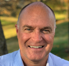 Professional headshot of a smiling businessman in light blue shirt