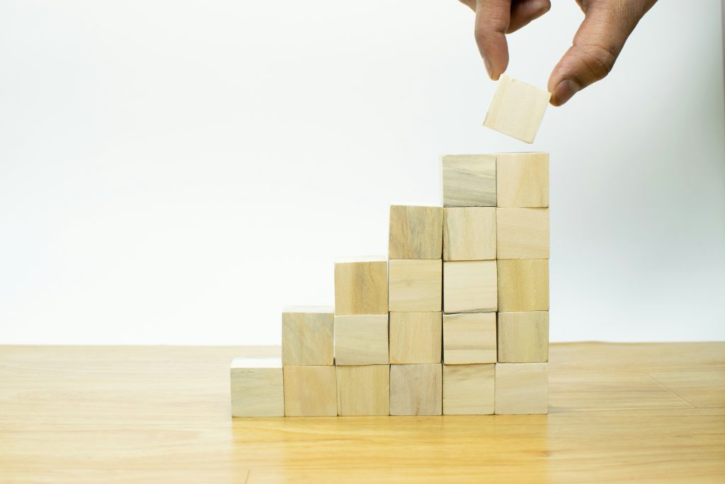 Hand placing a wooden block on top of a stepped stack of blocks
